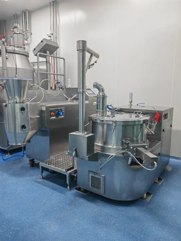 Operator at extruder spheronizer line in blue gown
