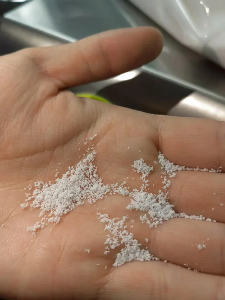 Hot melt coated pellets held in hand showing film coating result